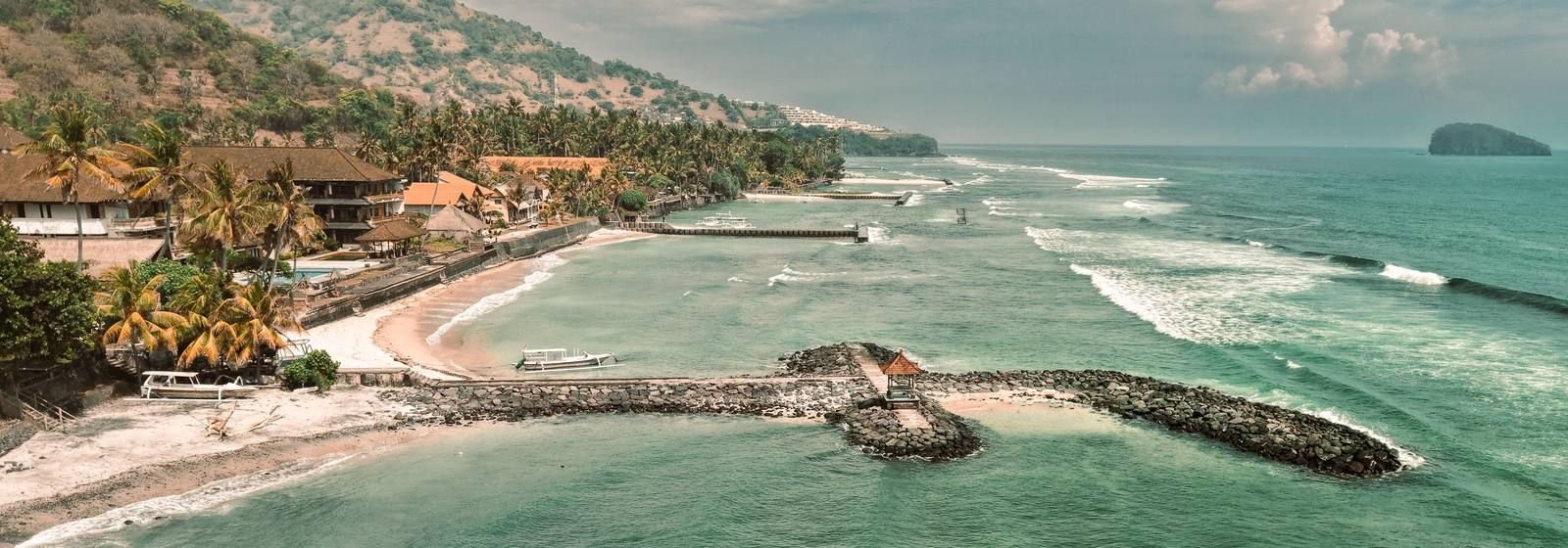 Aerial view of a Bali coast with hotels, a seawall and breakwaters